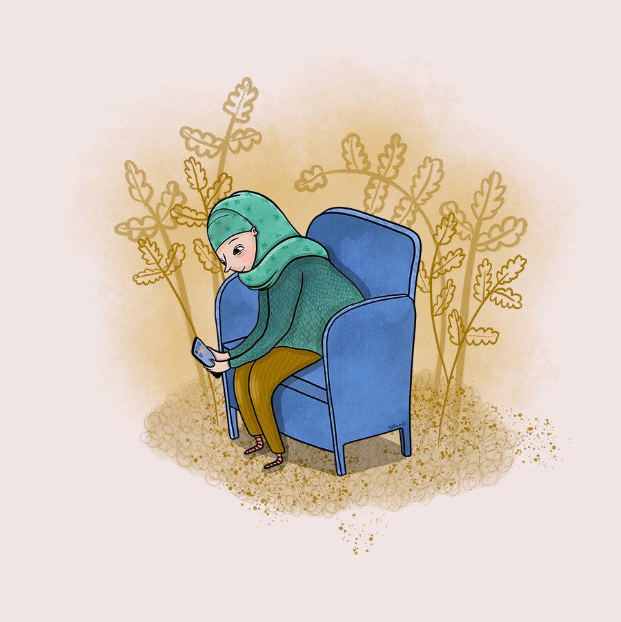 En kvinna i hijab sitter i en fåtölj och tittar på en mobil.